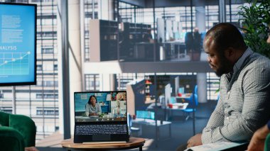 Çok ırklı iş adamları ofis lobisinde bir web video konferansına katılarak, küresel çok kültürlü bir çalışma ortamında uzak ortaklarla strateji ve müzakere noktaları alışverişinde bulundular. Kamera B.