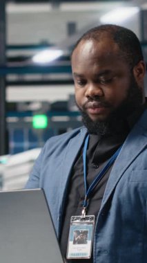 Verileri dizüstü bilgisayarda inceleyen, üretim tesisi performansını denetleyen ve yeniliği sembolize eden bir tesisteki dikey video güneş enerjisi uzmanı. Sanayi uzmanı üretim hattını denetliyor