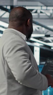 Dikey video Neşeli Veri Merkezi Sistem Yöneticisi otomatik betikler için kodu gözden geçirir. Jolly sunucu odası çalışanı ekipman üzerinde tanılama yapıyor, öngörü hatası algılaması yapıyor, kamera B