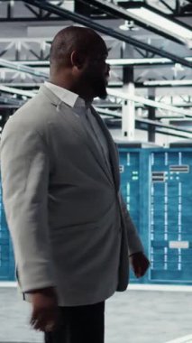 Vergi merkezinde yürüyen dikey video işadamı yatırım yapmadan önce tırabzan kapasitesini değerlendiriyor. İş depolama teçhizatı için inşa edilmiş sunucu çiftliğini denetleyen neşeli yönetim yöneticisi, kamera A