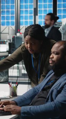 Bir güneş enerjisi tesisinde işbirliği yapan, sürdürülebilir alternatif enerji ve üretimi geliştirmek için planlar ve performans ölçümlerini gözden geçiren dikey Afrikalı Amerikalı mühendisler.