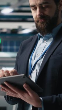 Dikey video endüstriyel erkek giysi uzmanı güneş enerjisi ekipmanlarını denetliyor, kalite kontrol ve üretim hattında verimlilik gösteriyor. Güneş panelleri üretiminde çalışıyorum. Kamera B.