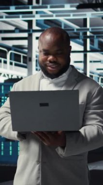 Veritabanı 'nda gülen bir mühendis sistem istikrarı için dizüstü bilgisayar kullanarak yazılım güncellemelerini yönetiyor. Sunucu çiftliğindeki mutlu çalışan performansı optimize ediyor, altyapıyı yapılandırıyor