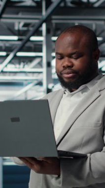 Veri merkezindeki dikey video mühendisi depolama dizilerini güncellemek için dizüstü bilgisayar kullanarak ağ sanal yapılandırmasını ayarlıyor. Sunucu odasında sabit performans için ayarları doğrulayan adam, kamera B