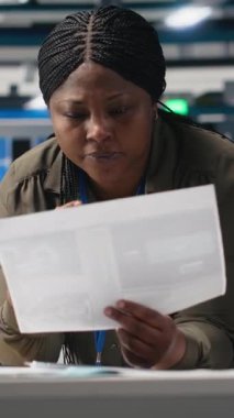 Dikey Video Mühendisliği uzmanı, güneş enerjisi fabrikasındaki kağıtlarla ilgili verileri kontrol ediyor, yüksek teknolojili güneş panelleri üretimi için üretim sistemlerinin değerlendirmelerini yapıyor. Kamera B.