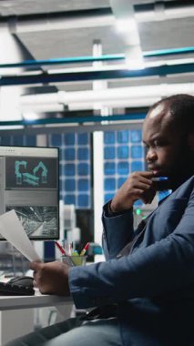 Dikey Afrikalı Amerikalı iş adamı güneş pili fabrikalarını inceliyor, fotovoltaik endüstrisinin üretim sürecini yürütüyor. Modern fabrikada uzman. Kamera A.