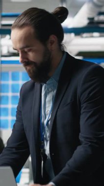 Takım elbiseli dikey video yöneticisi, modern imalat ve alternatif enerji verimliliğini simgeleyen bir güneş paneli fabrikasında teftiş yapıyor. Üretim planlama ve teknoloji
