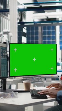 Dikey Video Erkek Teknoloji Uzmanı, PC 'nin yanındaki montaj hattını inceliyor, güneş enerjisi santralindeki fabrika operasyonlarını yöneterek yeşil enerjinin etkin kalite kontrolü ve taahhütünü sağlıyor