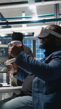 Dikey Video Photovoltaics imalat fabrikası analisti sistem performansını ve güneş panelleri üretim hattını izlemek için VR teçhizatıyla çalışıyor. Afrikalı Amerikalı uzman sanal gerçekliği kullanıyor. Kamera A.