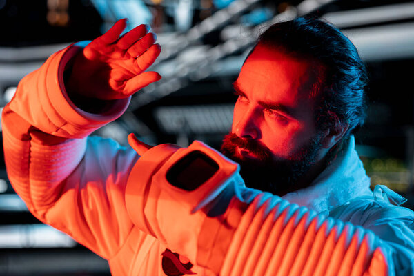 Крупный план осторожного астронавта, охраняющего от инопланетной угрозы, появившейся после нарушения среды обитания. Уставший космонавт, использующий руки, чтобы защитить себя от враждебного инопланетного присутствия