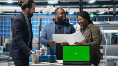 Danışmanlar ve fabrika analistleri güneş paneli tesisinde her detayı temiz enerji verimliliği ve güneş enerjisi yeniliğiyle aynı hizaya getirmek için bir kopya ekran üzerinde çalışıyorlar. Kamera B.