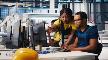 Afrika kökenli Amerikalı meslektaşlar güneş enerjisi üretim hattındaki güç verilerini analiz ediyor, takım çalışması masaüstü bilgisayarının etrafında toplandı. Mühendisler sürdürülebilir enerji için yapılandırmaları optimize ediyorlar. Kamera B.