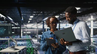 Veri merkezi sistem yöneticileri AI LLM görselleştirmelerini gözden geçirmek için dizüstü bilgisayar kullanıyorlar. Afrika kökenli Amerikan bilişim uzmanları sinirsel ağların çıktılarını analiz etmek için aygıt kullanırlar.