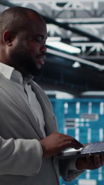 Yapay zeka algoritmaları geliştirmek için tablet kullanan dikey video Veri Merkezi yazılım geliştiricisi. Sunucu merkezindeki programcı dizüstü bilgisayarını kullanarak, sunucudaki sunucuları destekleyen veritabanlarını koruyor