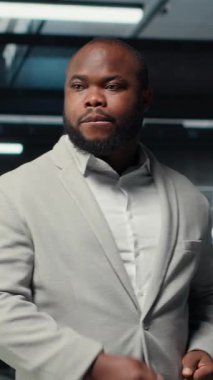 Veritabanı elektroniği ömrünü uzatmak ve ara vermekten kaçınmak için yıllık check-up yapan gülümseyen yönetimin dikey video portresi. Sunucu odasında yürüyen neşeli işçi, altyapı donanımlarını izliyor