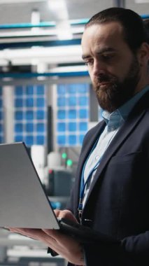 Güneş panellerinin üretim çıktısını izleyen takım elbiseli dikey video fabrikası müfettişi, profesyonel işgali ve temiz enerji gelişimine idari düzeyde katılımı yansıtıyor. Güneş enerjisi