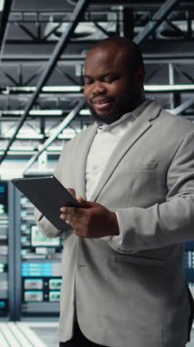 Tablet üzerinde çalışan kod hata ayıklama araçlarına bakan dikey video Neşeli veri merkezi programcısı. Aygıt dokunmatik ekranında yazan, betik otomatik görevleri yazan sunucu çiftliği bilişim uzmanı, kamera A