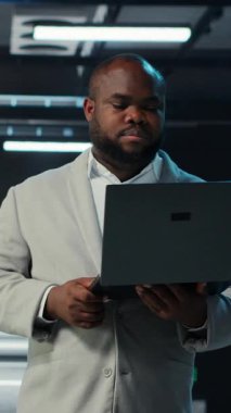 Ana bilgisayarlar için yazılım güncellemeleri yaparak dizüstü bilgisayarda kodlama yapan dikey video veri merkezi mühendisi. Sunucu çiftliği bilişim uzmanının klavyeye yazması, altyapının optimize edilmesi, kamera B