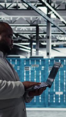 Dikey video veri merkezi mühendisi dizüstü bilgisayar kullanarak yapay zeka kullanan yönetim araçları kullanıyor. Sunucu çiftliği çalışanı sunucu kümelerini denetliyor, yapay zeka kullanarak ağ topolojilerini güncelliyor