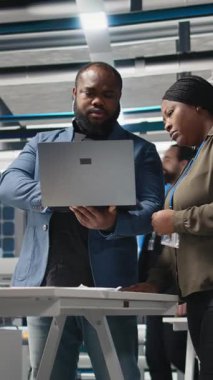 Dikey Video Afrikalı Amerikalı endüstriyel iş arkadaşları güneş panelleri için üretim hattı üzerinde takım çalışması yapıyorlar, teknik içgörü ve takım çalışmasını birleştirerek temiz enerji altyapısını ileriye taşıyorlar. Kamera A