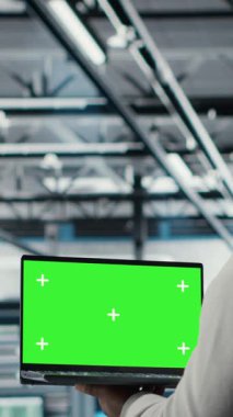 Sinir ağı yapay zekasını izlemek için izole ekran dizüstü bilgisayar kullanan dikey video veri merkezi yönetimi. Sunucu odası çalışanı, platformlara güç veren makine öğrenme süreçlerini denetlemek için maket defteri kullanıyor. Kamera B