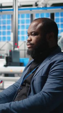 Dikey Video Afrikalı Amerikalı usta mühendis bir güneş teknolojisi fabrikasında yeşil enerji hedeflerine ulaşmak için fabrika faaliyetlerini gözden geçiriyor. Uzman, üretim verimliliği için tablet kullanıyor