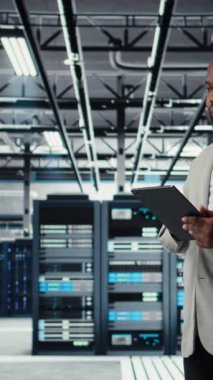 Endüstriyel veri merkezinde dikey video bilişim uzmanı altyapı performansını analiz ediyor, devre dışı kalma ve ekipman arızalarını en aza indiriyor. Sunucu çiftlik işçisi iş yapıyor, anomaliyi otomatikleştiriyor