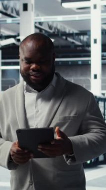 Sistem istikrarı için yazılım güncellemelerini yönetmek için tablet kullanan dikey video Neşeli veri merkezi programcısı. Neşeli sunucu odası IT uzmanı aygıtla performansı optimize ediyor, yapılandırıyor