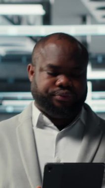 Sistem istikrarı için yazılım güncellemelerini yönetmek için tablet kullanan dikey video Neşeli veri merkezi programcısı. Neşeli sunucu odası IT uzmanı aygıtla performansı optimize ediyor, yapılandırıyor