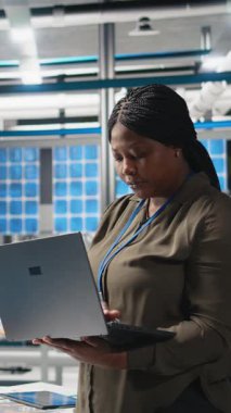 Fabrikadaki bir siyah teknisyenin dikey video portresi güneş panelleri üretim hattını denetleyerek üretim sürecinin denetlenmesini sağlar. Temiz enerji ve sürdürülebilirlik hedeflerine ulaşmak