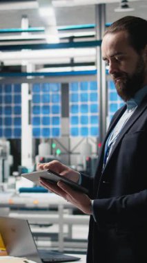 Dikey video endüstriyel erkek giysi uzmanı güneş enerjisi ekipmanlarını denetliyor, kalite kontrol ve üretim hattında verimlilik gösteriyor. Güneş panelleri üretiminde çalışıyorum. Kamera A.