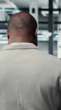 Yüksek teknoloji veri merkezi tesisinde yürüyen dikey video idarecisi sistem istikrarını kontrol ediyor. Bilgi işlem uzmanı sunucu odasını denetliyor, süper bilgisayarları yapılandırıyor, performansı optimize ediyor