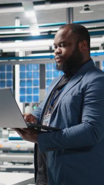 Bir güneş panelindeki dikey video Afrikalı Amerikalı yönetmen performans ve verimlilik ölçümlerini izliyor, liderliği gerçek zamanlı kalite kontrolü ve stratejik iş dünyasıyla birleştiriyor