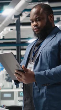 Dikey Video Siyah Sanayi uzmanı yenilenebilir enerji başarısını sürdürmek için yenilik ve verimliliği güvence altına alan bir güneş teknolojisi tesisinde üretim verilerini inceliyor. Çevre dostu sürdürülebilir çözümler