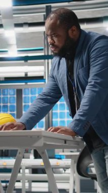 Dikey Video Ustası Mühendis, imalat fabrikasında alternatif enerji sistemleri üzerinde çalışan fotovoltaikler için üretim hattı ekipmanlarını gözden geçiriyor. Güneş enerjisi endüstrisinde uzman.