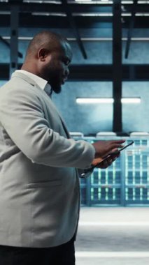 Dikey video veri merkezi mühendisi sunucu donanımını ayarlıyor yapay zeka işleme işlemleri yapıyor. Yönetici, sunucu dizilerinin eğitim veri tabanlarıyla ilgilenmesini denetler