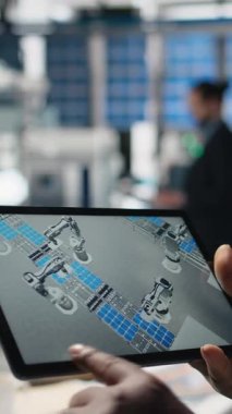 Fotovoltaik fabrikasındaki tablet üzerindeki verileri inceleyen dikey video güneş enerjisi teknisyeni, güneş enerjisi yeniliği için üretim tesisi performansı ve üretim hattını denetliyor. Alternatif enerji. Kamera.