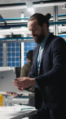 Takım elbiseli dikey video yöneticisi, modern imalat ve alternatif enerji verimliliğini simgeleyen bir güneş paneli fabrikasında teftiş yapıyor. Üretim planlama ve teknoloji