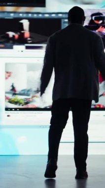 Dikey video Neşeli kullanıcı metaevrende sınırsız video içeriği özgürlüğünü kutluyor. Mutlu adam dev dijital duvarın önünde kollarını açmış çevrimiçi video kanallarının bolluğundan zevk alıyor.