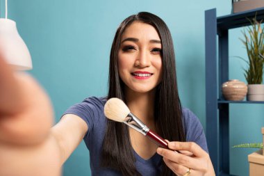 Moda blogcusu canlı yayın dersi kaydediyor, makyaj malzemelerini sunuyor ve izleyicilerini kendine çekiyor. İzleyicileri için kozmetik fırçalar ve makyaj teknikleri hakkında görüşlerini paylaşıyor..