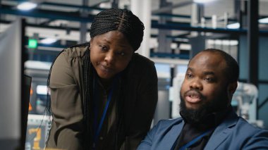 Siyahi mühendisler teknisyenleri bir güneş paneli fabrikasında fikirlerini paylaşıyor, projeleri gözden geçiriyor ve yenilenebilir enerji üretimini ve sürdürülebilir yeniliği geliştirmek için fikirlerini paylaşıyor. Kamera B.