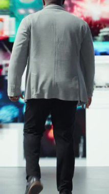 Dikey video, kolları açık, büyük dijital video duvarına bakan, sonsuz eğlence seçiminden yararlanarak mutluluğu ifade eden aşırı neşeli bir adam. Neşeli izleyiciler sonsuz akışa erişmenin keyfini çıkarıyor