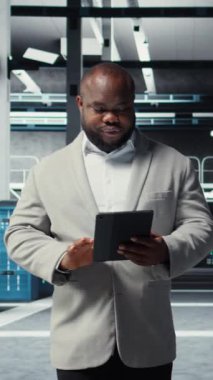 Veritabanında tablet kullanarak iş yükleri için altyapıyı sağlayan dikey gülümseyen bir yönetici. Sunucu çiftliğindeki neşeli bilişim uzmanı paralel işleme için yüksek teknoloji sunucu kümeleri kullanıyor