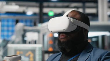 Siyah fotovoltaik fabrikası uzmanı, güneş panellerini yerleştirmek için robotik kollarla çalışan dijital güneş pillerini monte etmek için VR gözlükleri kullanıyor. Mühendis sanal gerçeklikte makineler kullanır. Kamera A.