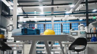 Yenilenebilir enerji üretim hattı için fotovoltaik ölçümler gösteren robotik kollar, güvenlik donanımı ve PC monitörlerinin yer aldığı yüksek teknolojili bir güneş panelleri fabrikasında boş mühendislik çalışma alanı.