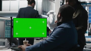 Güneş enerjisi çeşitliliği ekibi yeşil ekranın yanındaki bilgisayarı inceliyor, üretim sırasında hatalar buluyor ve temiz enerji operasyonlarının optimize edilmesine yardım ediyor. Fotovoltaik. Kamera A.