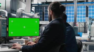 Güneş panelleri denetleme grubu yeşil ekranın yanındaki pc üzerinde verileri gözden geçirir, süreç denetimi sırasında hatalar bulur ve yenilenebilir enerji operasyonlarının optimize edilmesine yardımcı olur. Fotovoltaik fabrikası. Kamera A.