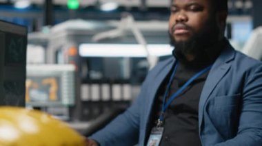 Siyahi endüstriyel uzman, güneş paneli fabrikası kurarak, temiz sürdürülebilir enerji üzerinde çalışarak, bilgisayar üzerindeki montaj sürecini inceliyor. Üretim akışı için mühendislik yeniliği. Kamera A.