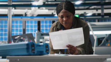 Güneş enerjisi fabrikasındaki kağıtların verilerini kontrol eden kara mühendislik uzmanı yüksek teknolojili güneş panelleri üretimi için üretim sistemlerinin değerlendirmelerini yapıyor. Kamera A.