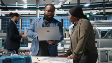 Siyahi mühendislik uzmanları ve yöneticileri bir güneş enerjisi üretim tesisindeki operasyonel iş akışlarını inceliyorlar. Yenilenebilir enerji üretimi ve gelişimi için takım çalışması entegre ediliyor. Kamera B.